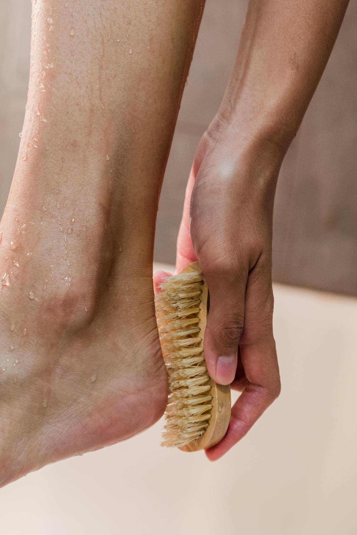 Hand gently scrubs foot with a brush to maintain hygiene in a close-up view.